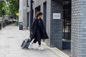 una mujer caminando por una acera con una maleta en YOTEL London Shoreditch, en Londres