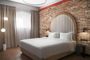 Radisson RED Gdansk, Wyspa Spichrzów في غدانسك: غرفة نوم بسرير كبير وبجدار من الطوب
