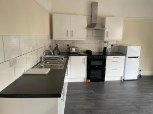 une cuisine avec des placards blancs et un comptoir noir dans l'établissement Large 4 Bedroom Sleeps 8, Spacious Apartment for Contractors and Holidays near Bedford Centre - 1 FREE PARKING SPACE & FREE WIFI, à Bedford