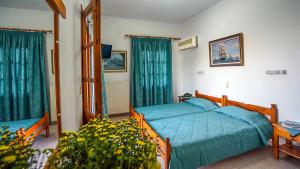 a bedroom with a bed with blue sheets and windows at Effie Hotel in Skala