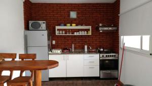 a kitchen with white cabinets and a brick wall at DUPLEX TIERRA DE MAR 2 in San Clemente del Tuyú