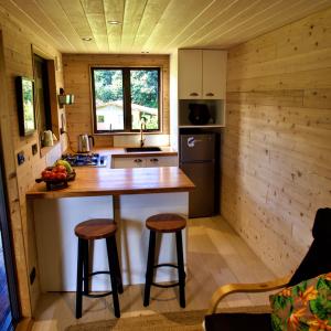 a kitchen in a log cabin with a counter and stools at 'ARE PEPE one bedroom container style unit in Rarotonga