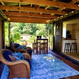 a screened in porch with wicker chairs and a glass table at 'ARE PEPE one bedroom container style unit in Rarotonga
