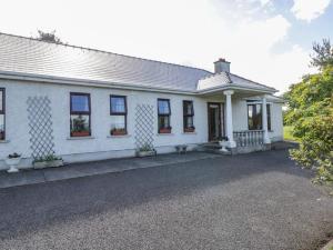 a white house with windows and a driveway at Belladrihid Cottage in Ballysadare