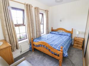 a bedroom with a wooden bed and two windows at Belladrihid Cottage in Ballysadare