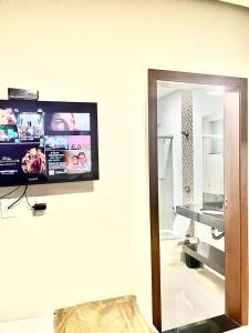 telewizor z płaskim ekranem na ścianie z lustrem w obiekcie Casa Família Paraíso w mieście Capitólio