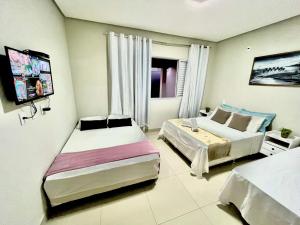 ein Schlafzimmer mit 2 Betten und einem TV. in der Unterkunft Casa Família Paraíso in Capitólio