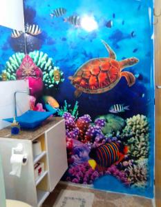 una tortuga bajo el mural del océano en un baño en Suítes Cocaia en Ilhabela