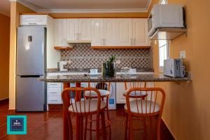 a kitchen with white cabinets and a counter with stools at Inma Apartment Montaña La Data in San Bartolomé de Tirajana
