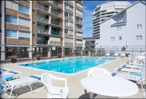una piscina con sillas blancas y un edificio en Surfside 84 #31, en Ocean City