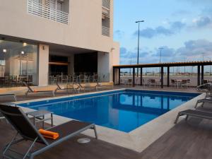 a swimming pool with chairs and tables and a building at Hotel Yes Inn Nuevo Veracruz in Veracruz