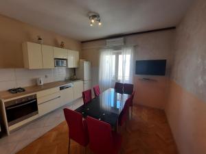 マカルスカにあるApartments with a parking space Makarska - 12211のキッチン(黒いテーブル、赤い椅子付)