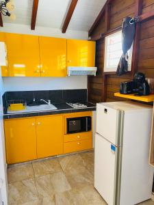 een keuken met gele kasten en een witte koelkast bij Obuncoeur in Le Gosier