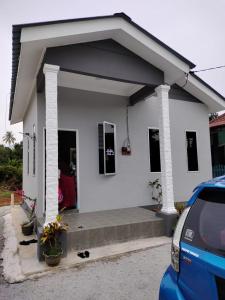 a white house with a car parked in front of it at Wanna Homestay in Jertih +2 photos