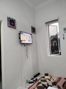 1 dormitorio con 1 cama y TV en la pared en Wanna Homestay, en Jertih