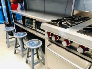 a kitchen with two stools next to a stove at ROOMIES HOSTEL Roma in Mexico City