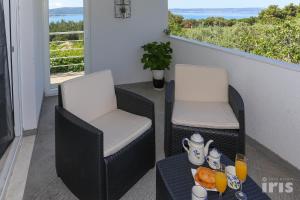 dwa krzesła i stół z jedzeniem na balkonie w obiekcie Apartments with a parking space Kastel Sucurac, Kastela - 12445 w mieście Kaštela