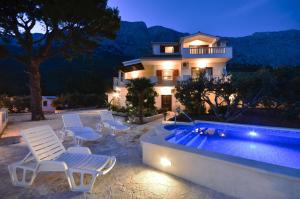 uma casa com cadeiras e uma piscina à noite em Family friendly apartments with a swimming pool Baska Voda, Makarska - 12442 em Baska Voda