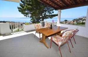 uma mesa de madeira e cadeiras numa varanda com vista em Family friendly apartments with a swimming pool Baska Voda, Makarska - 12442 em Baska Voda