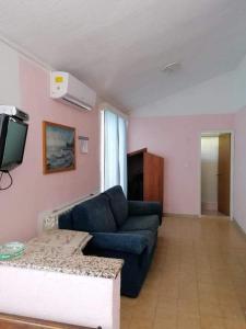 a living room with a blue couch and a tv at Apartments and rooms by the sea Kampor, Rab - 12473 in Rab