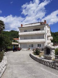 a large white building with a stone wall at Apartments and rooms by the sea Kampor, Rab - 12473 in Rab