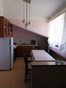a kitchen with a table and a white refrigerator at Apartments and rooms by the sea Kampor, Rab - 12473 in Rab