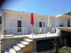 une maison blanche avec deux parasols blancs et des escaliers dans l'établissement Apartments by the sea Kabli, Peljesac - 12475, à Janjina