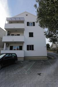 um edifício branco com um carro estacionado em frente em Apartments with a parking space Supetar, Brac - 12489 em Supetar
