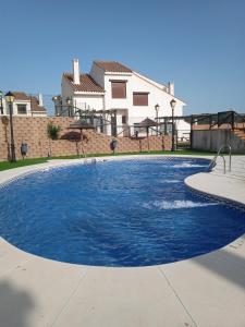 una gran piscina de agua azul frente a una casa en Casa Rural Sierramagna de 2 Dormitorios, en El Ronquillo