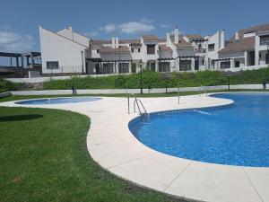a pool in a yard with houses in the background at Casa Rural Sierramagna de 2 Dormitorios in El Ronquillo