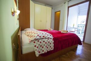 Schlafzimmer mit einem Bett mit einer roten und weißen Bettdecke in der Unterkunft Apartments with a parking space Baska Voda, Makarska - 12543 in Baška Voda