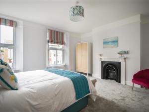 a white bedroom with a bed and a fireplace at 55 Queen Street in Seaton