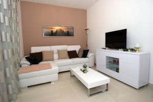een woonkamer met een witte bank en een tv bij Apartments with a parking space Zagreb - 12573 in Zagreb