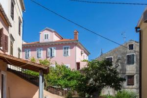 a pink house in the middle of some buildings at Apartments by the sea Mali Losinj (Losinj) - 12634 in Veli Lošinj