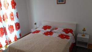 een slaapkamer met een bed met rode bloemen erop bij Apartments with a parking space Vinisce, Trogir - 12637 in Vinišće