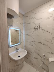 een witte badkamer met een wastafel en een spiegel bij 44m luxury room near downtown and all services in Amman