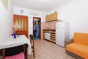 a kitchen with a table and a white refrigerator at Apartments by the sea Prizba, Korcula - 12648 in Prizba