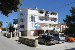 parking z samochodami zaparkowanymi przed budynkiem w obiekcie Apartments by the sea Novalja, Pag - 12413 w Novalji