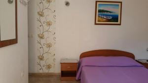 sypialnia z fioletowym łóżkiem i zdjęciem na ścianie w obiekcie Apartments by the sea Novalja, Pag - 12413 w Novalji