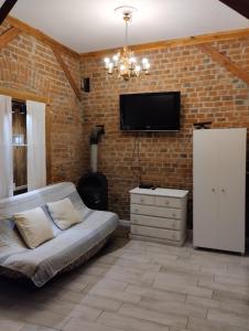 a living room with a couch and a tv on a brick wall at Apartamenty nad Łyną in Olsztyn