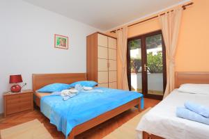 een slaapkamer met 2 bedden met blauwe lakens en een raam bij Apartments by the sea Duce, Omis - 12687 in Dugi Rat