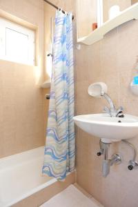 ein Bad mit einem Waschbecken und einem Duschvorhang in der Unterkunft Apartments by the sea Duce, Omis - 12687 in Dugi Rat