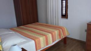 ein Schlafzimmer mit einem Bett mit gestreifter Decke in der Unterkunft Apartments with a parking space Savar, Dugi otok - 12762 in Brbinj