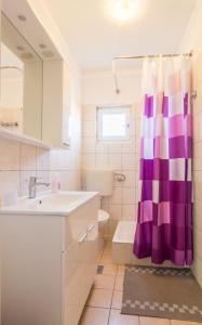 ein Badezimmer mit einem Waschbecken und einem lila Duschvorhang in der Unterkunft Apartments with a parking space Biograd na Moru, Biograd - 12796 in Biograd na Moru