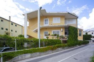 a yellow house with a balcony on a street at Apartments with parking space Podgora, Makarska - 12816 in Podgora