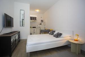 a bedroom with a large white bed and a kitchen at Apartments with parking space Podgora, Makarska - 12816 in Podgora