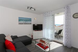 uma sala de estar com um sofá e uma televisão em Apartments with a parking space Podstrana, Split - 12837 em Podstrana