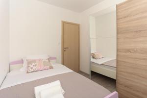 um pequeno quarto com uma cama e um espelho em Apartments with a parking space Podstrana, Split - 12837 em Podstrana