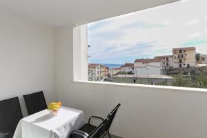 um quarto branco com uma mesa e cadeiras e uma janela em Apartments with a parking space Podstrana, Split - 12837 em Podstrana