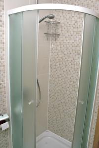 La salle de bains est pourvue d'une douche avec une porte en verre. dans l'établissement Apartments with a parking space Bilo, Primosten - 12870, à Primošten